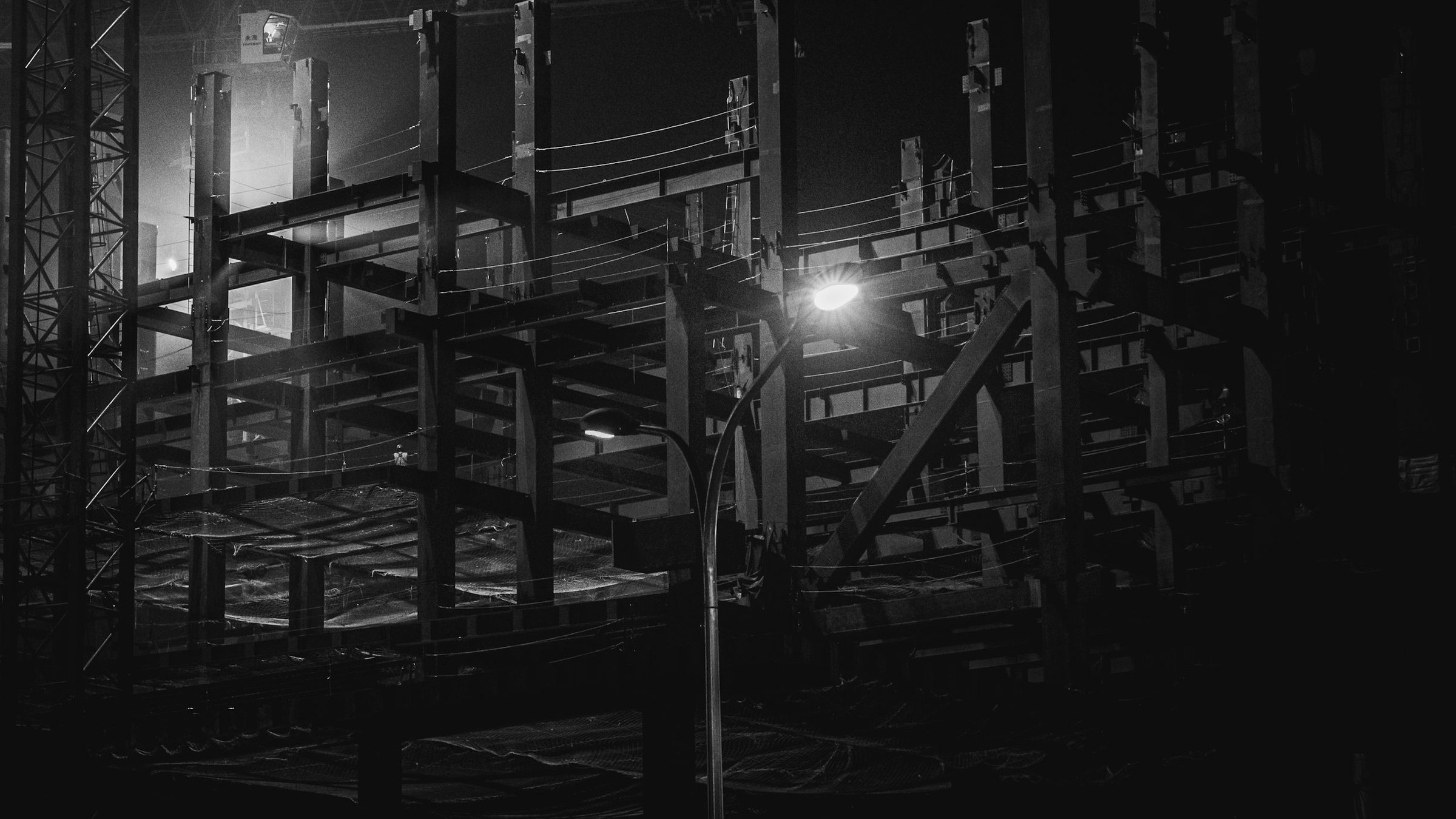 Estrutura de obra em contraluz, com vigas e andaimes